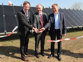 Männern schneiden Band vor einen Photovoltaik Anlage durch